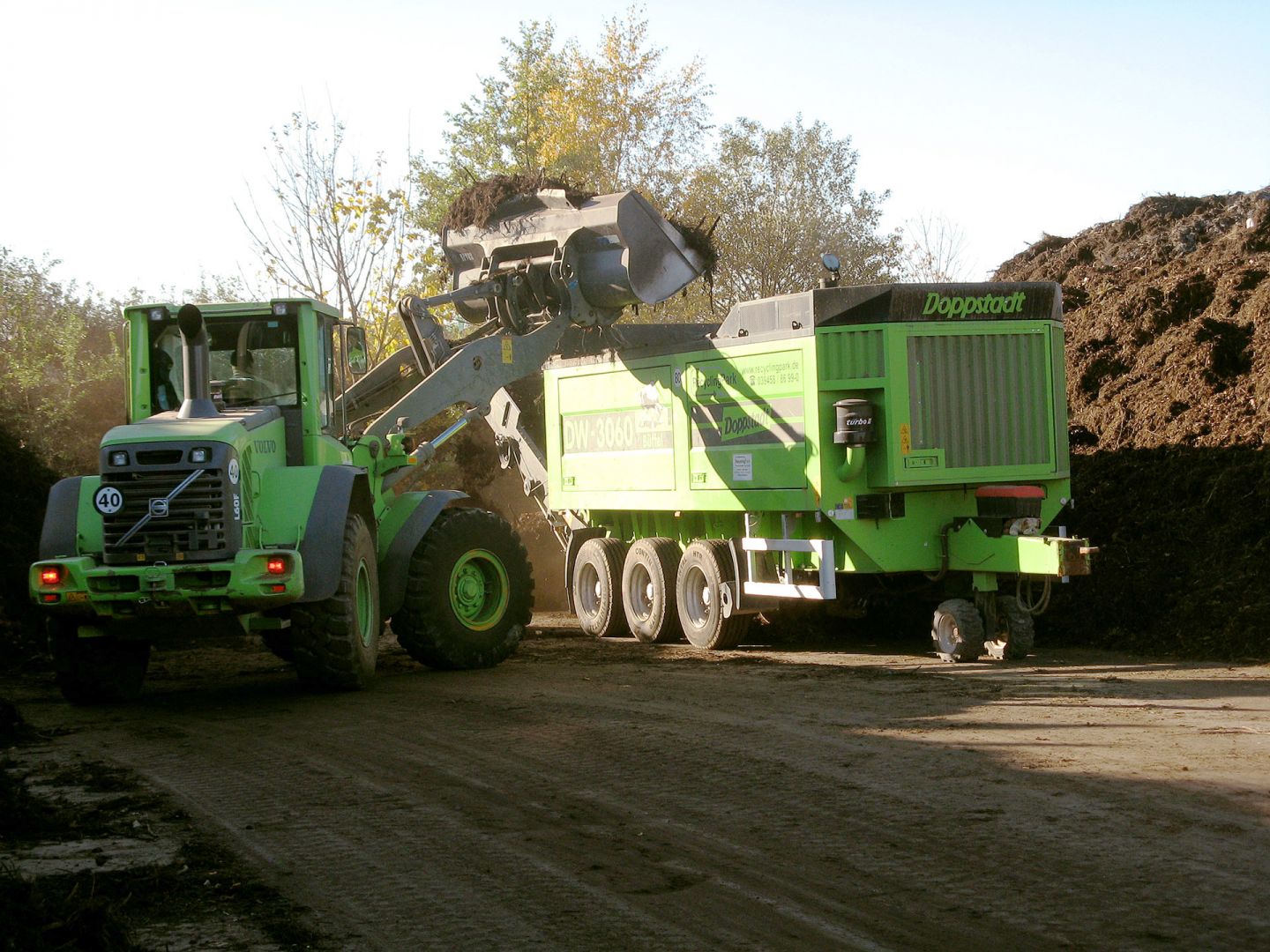Baufahrzeuge beim Bearbeiten und Anliefern des Schuttmaterials